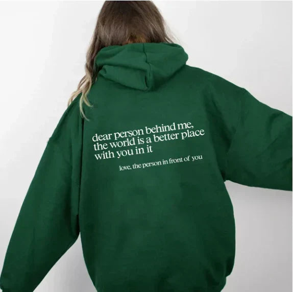 Back view of a woman wearing a dark green inspiring slogan casual hoodie indoors