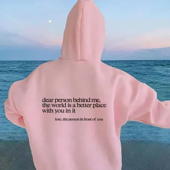 Back view of a woman wearing a pink inspiring slogan casual hoodie by the sea