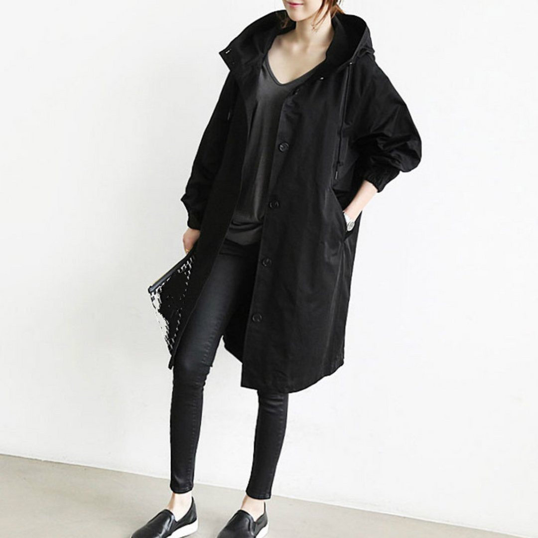 Woman wearing a black long hooded trench coat with skinny jeans and black shoes