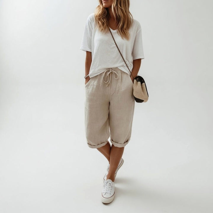Full view of a woman in casual khaki bermuda shorts and white sneakers