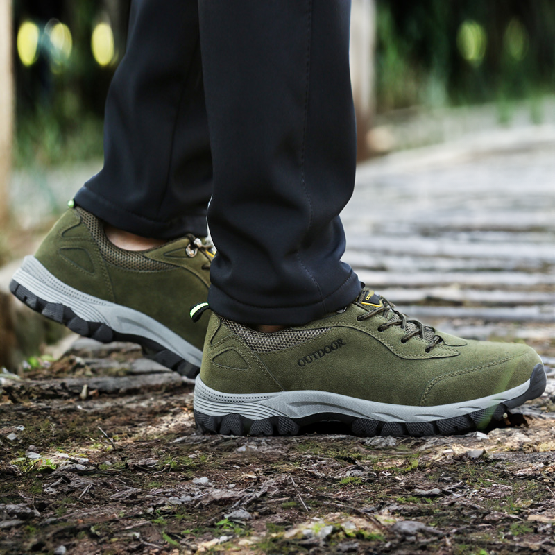 Green men's orthopedic hiking shoes worn outdoors on a wooden path