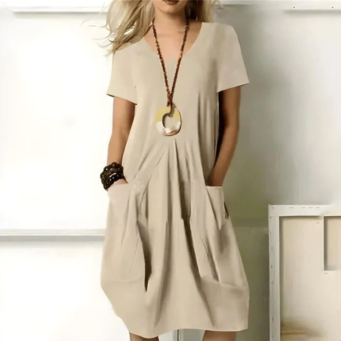 Woman wearing the neutral beige short sleeve everyday dress with functional pockets