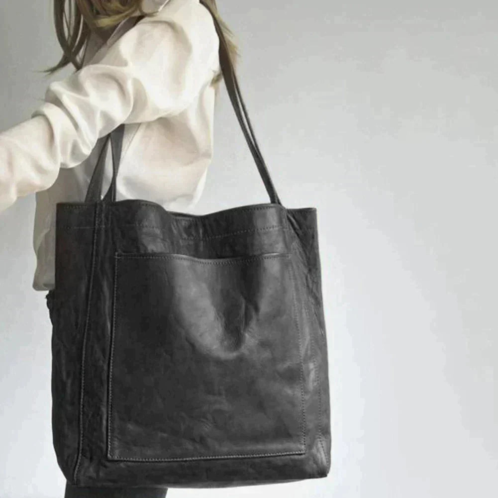 Model carrying the sleek black leather handbag version