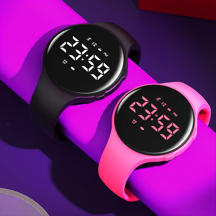 Black and pink children's fitness watches with illuminated digital displays on a purple surface