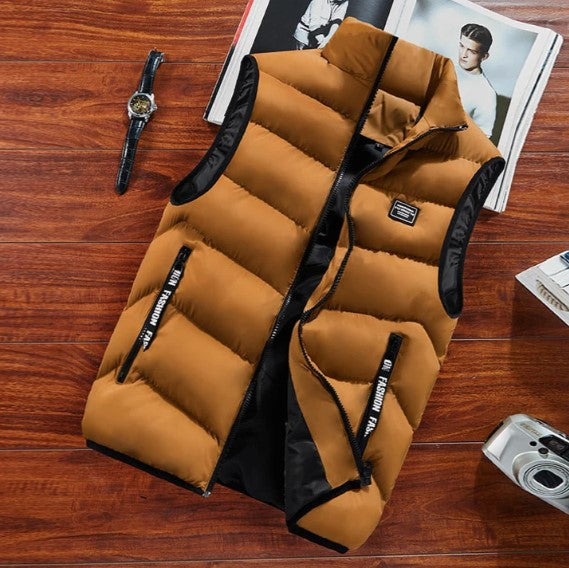 Mustard men's puffer zip up vest with stand collar and zippered pockets displayed on a wooden table