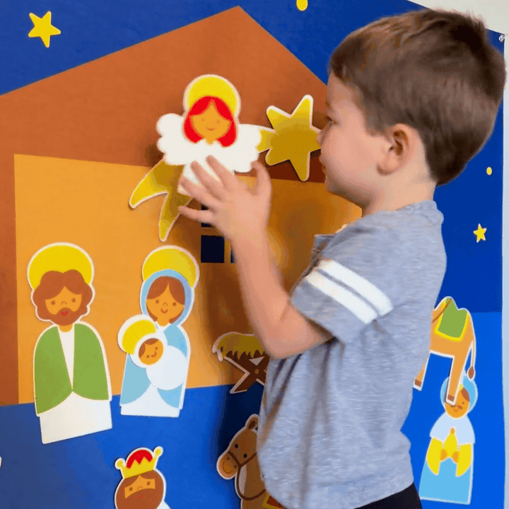 Close-up of a child placing the angel figure onto the felt nativity background