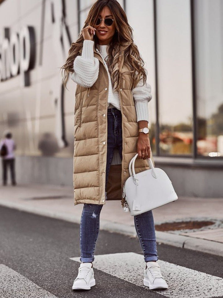 Close-up view of the beige long quilted vest fabric, texture, and snap-button closure details.