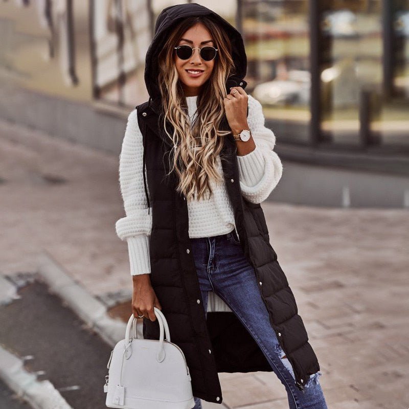 Woman wearing a black knee-length quilted bodywarmer with hood and sunglasses