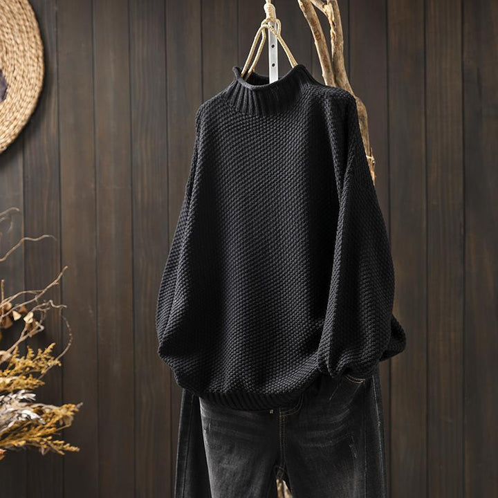 Black women's cozy knitted pullover sweater displayed on a rustic hanger