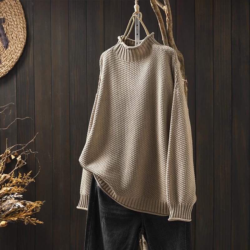 Beige women's cozy knitted pullover sweater hanging against a rustic wooden background