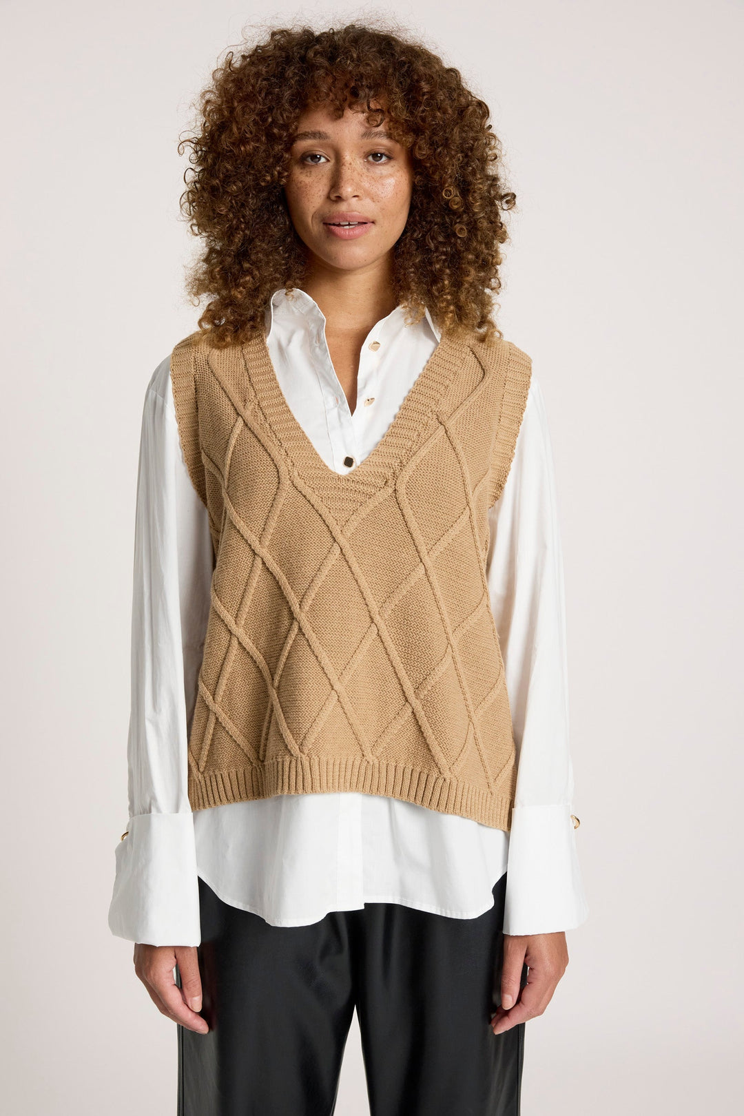 Close-up portrait of a model wearing the mocha patterned knit vest and white collared shirt