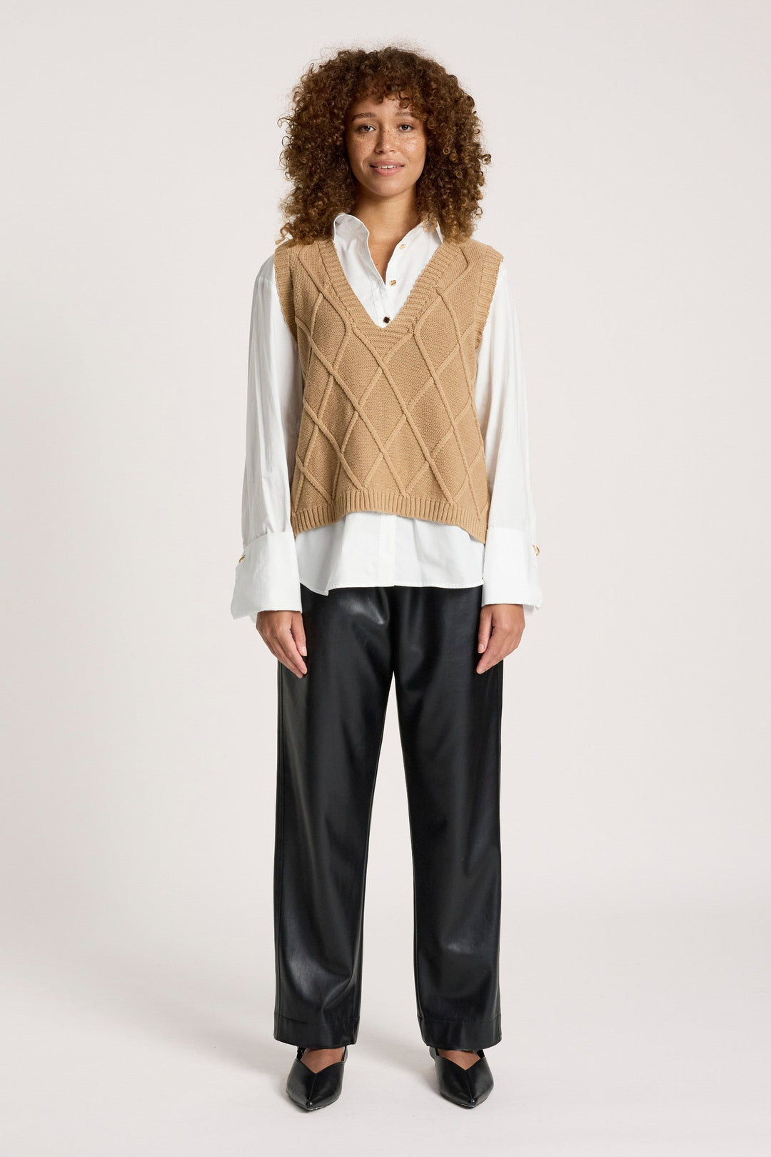 Full-body view of a model styling the mocha knit vest with black trousers and black heels