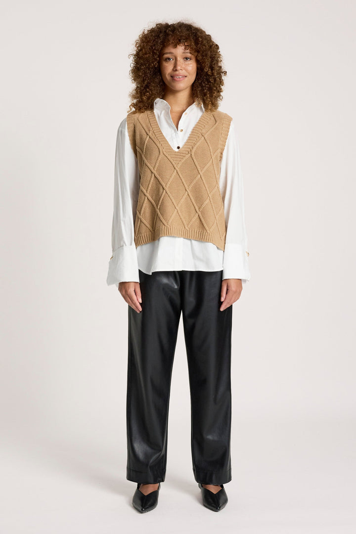 Full-body view of a model styling the mocha knit vest with black trousers and black heels
