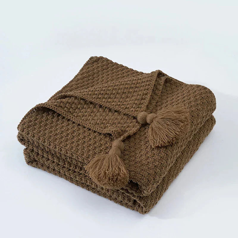 Detailed view of tassels on a cream colored knitted throw