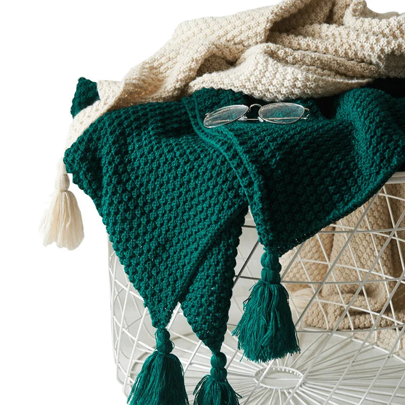 Close-up of a deep green textured knitted blanket with fringe tassels