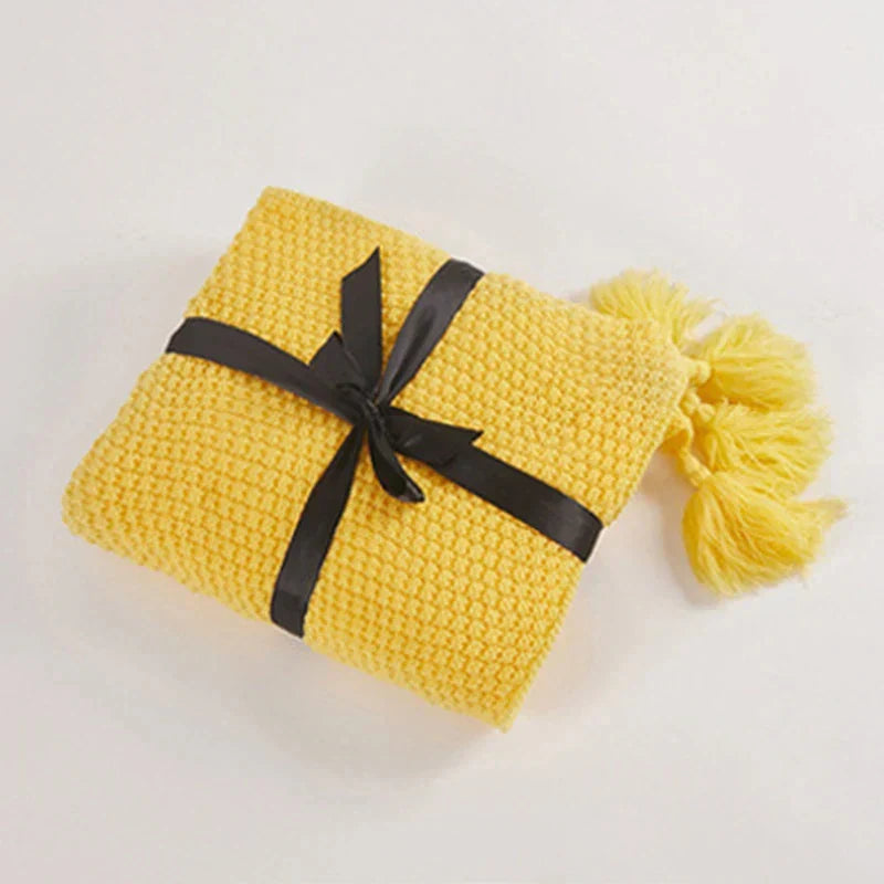 Nordic knitted blanket with tassels draped over a modern sofa