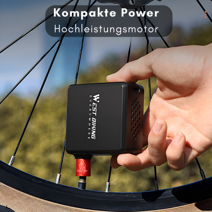 Hand holding compact black electric bike pump next to tire