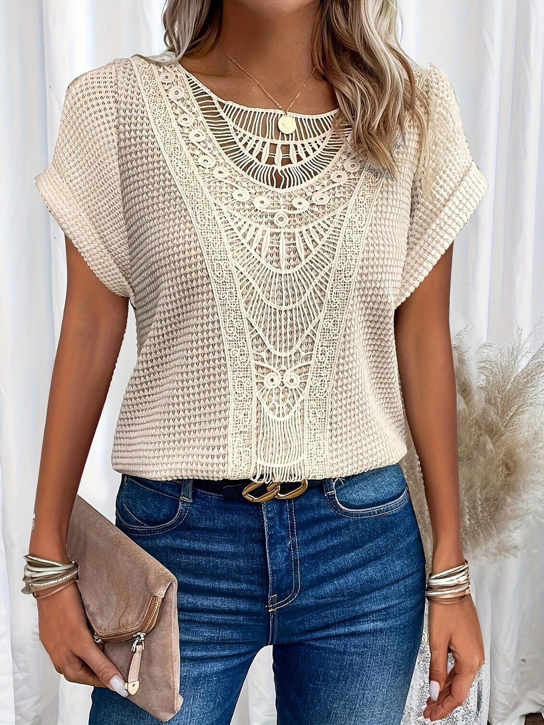 Woman wearing a beige crochet lace short sleeve casual top with blue jeans