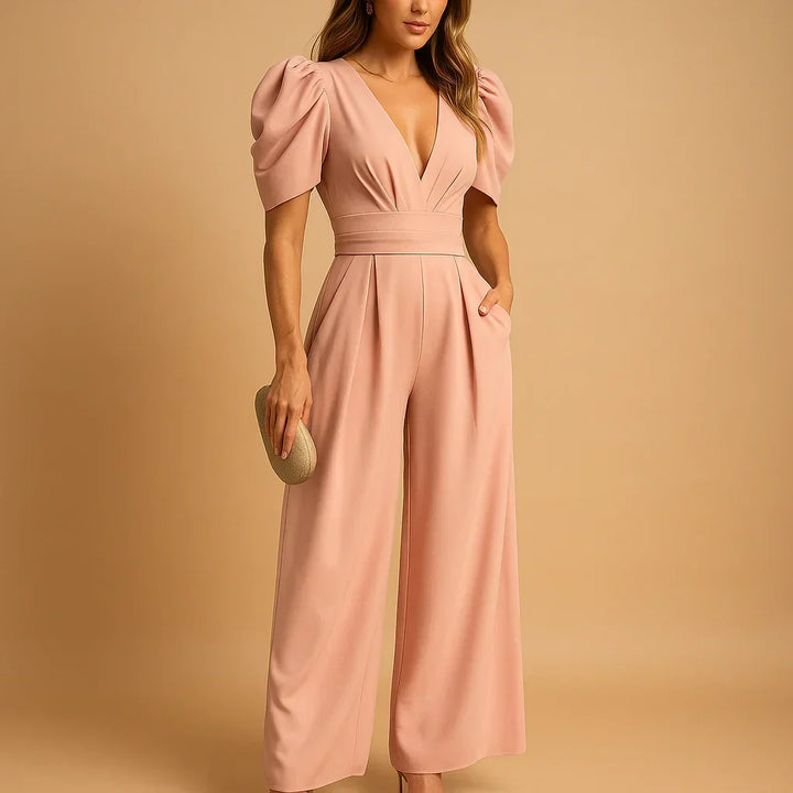 Woman wearing a peach puff-sleeve tailored jumpsuit with a wide-leg silhouette