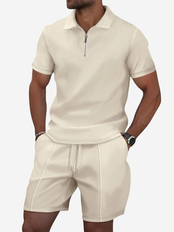 Man wearing beige zip-neck polo and shorts lounge set against a white background