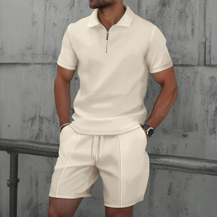 Man posing outdoors wearing beige matching polo shirt and shorts set