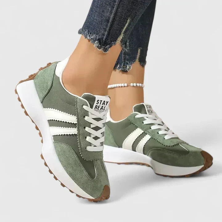 Green women's retro walking sneakers paired with jeans