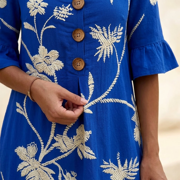 Close-up of wooden buttons and raised floral embroidery on a blue midi dress