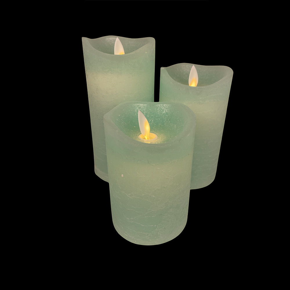 Three different sized flameless LED candles casting a soft glow in the dark