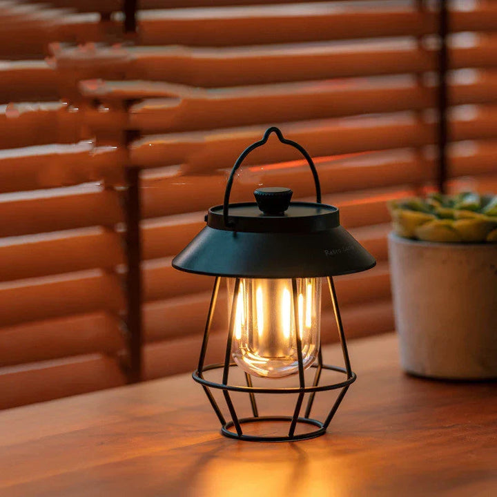 Portable USB rechargeable vintage camp lamp placed on a wooden picnic table