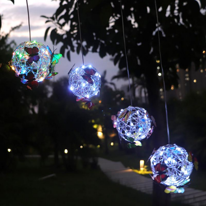 Multiple solar butterfly garden lights hanging outdoors at dusk