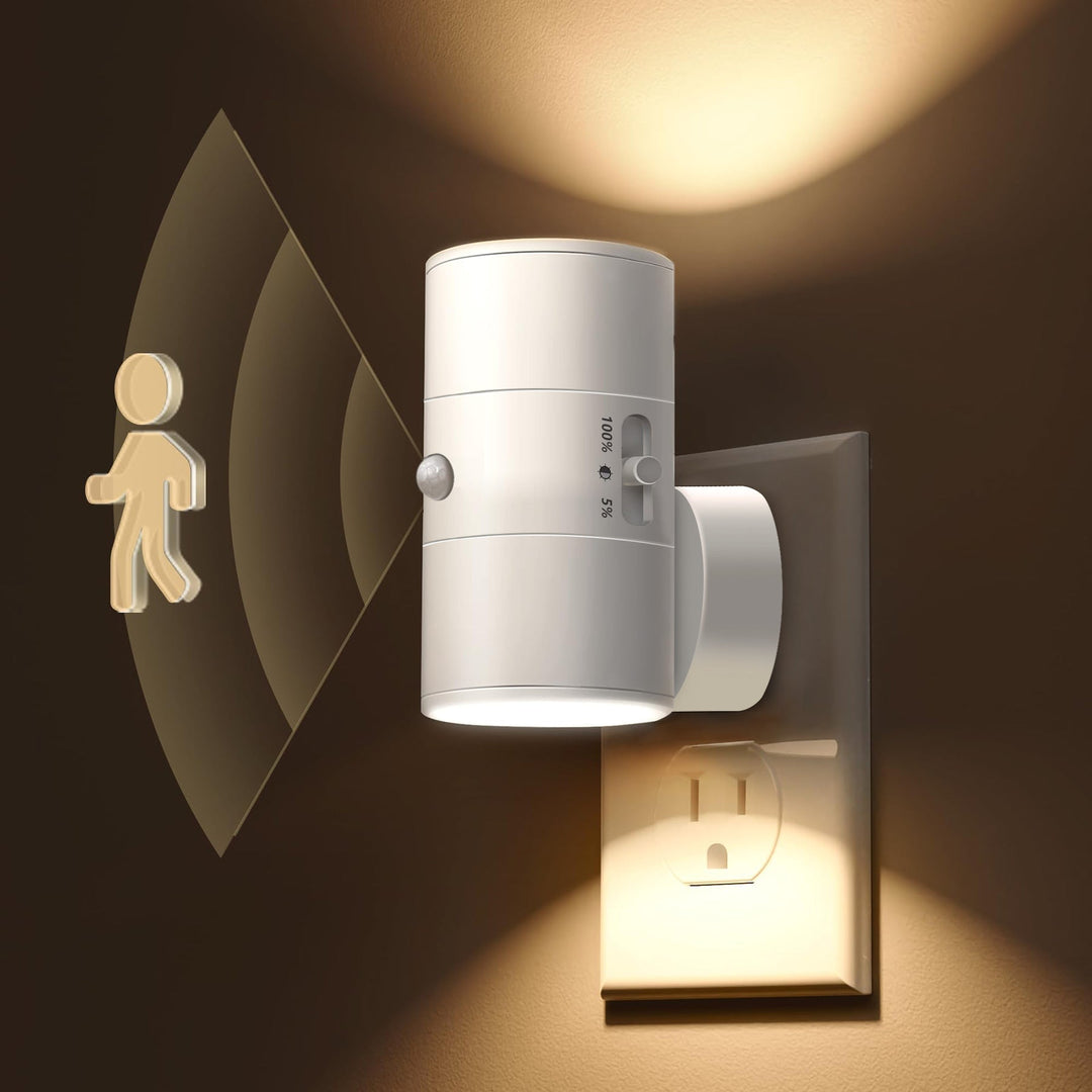 White plug-in LED motion sensor night light plugged into a wall outlet illuminating a hallway