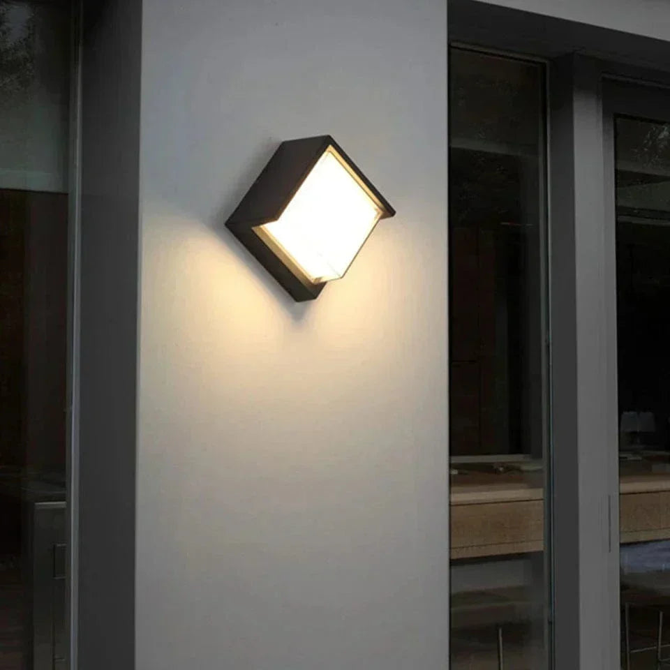 Contemporary angular outdoor wall light illuminating a modern exterior white wall