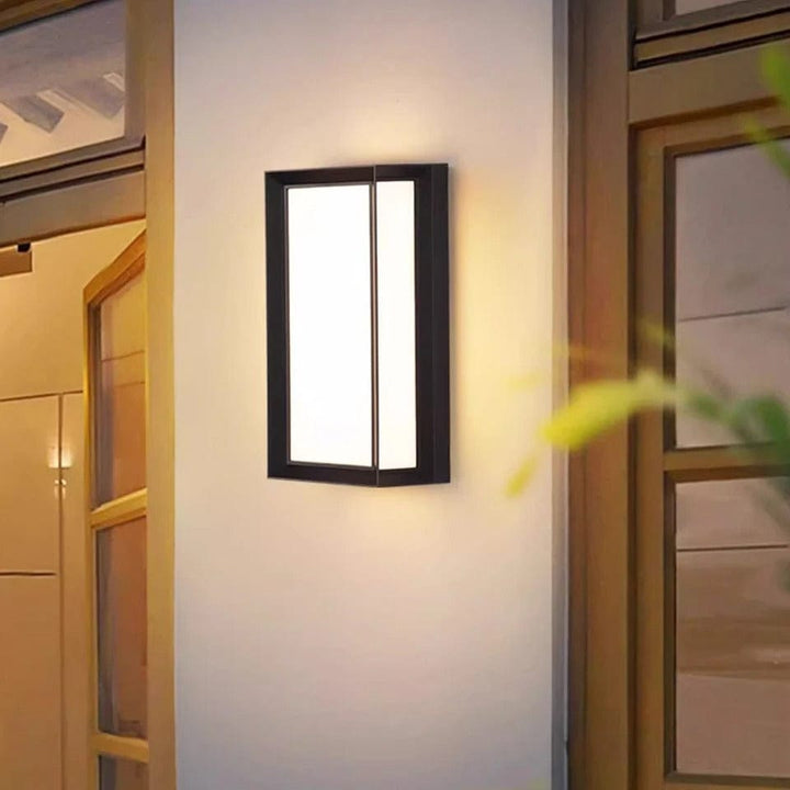 Modern LED outdoor wall light illuminating a dark exterior brick wall at night