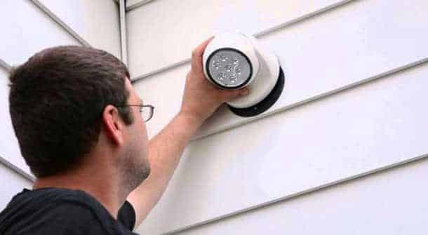 Man easily installing the wireless LED sensor lamp onto an exterior wall