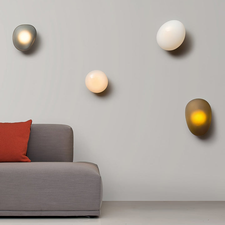 Multiple modern LED wall lamps in various colors and sizes mounted on a living room wall