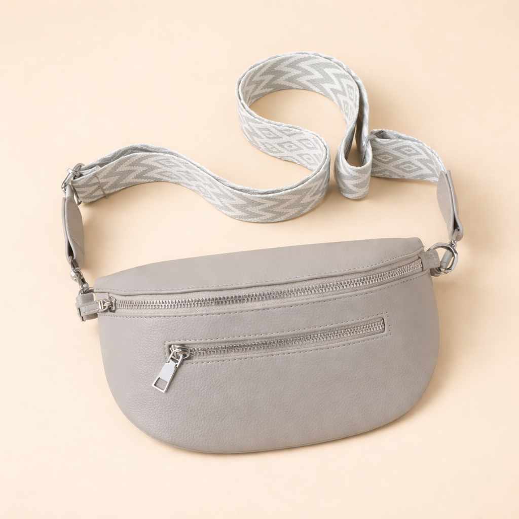 Grey crescent crossbody belt bag laid flat with adjustable strap
