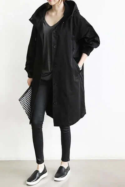 Woman wearing a black lightweight waterproof rain cape with pockets