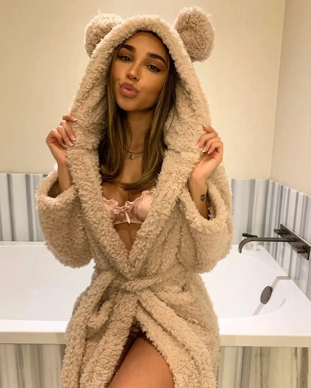 Woman wearing a khaki fluffy hooded bathrobe with bear ears in a bathroom