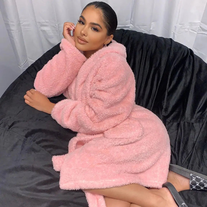 Woman relaxing on a bean bag wearing a pink fluffy hooded bathrobe