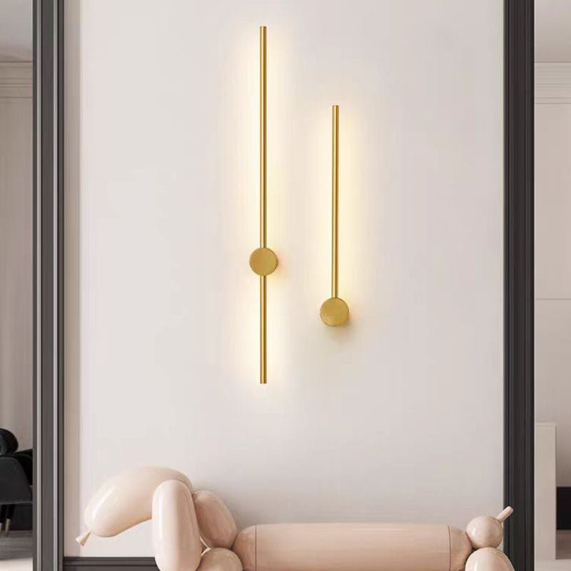 Gold linear LED wall lamp fixtures mounted vertically on a neutral wall