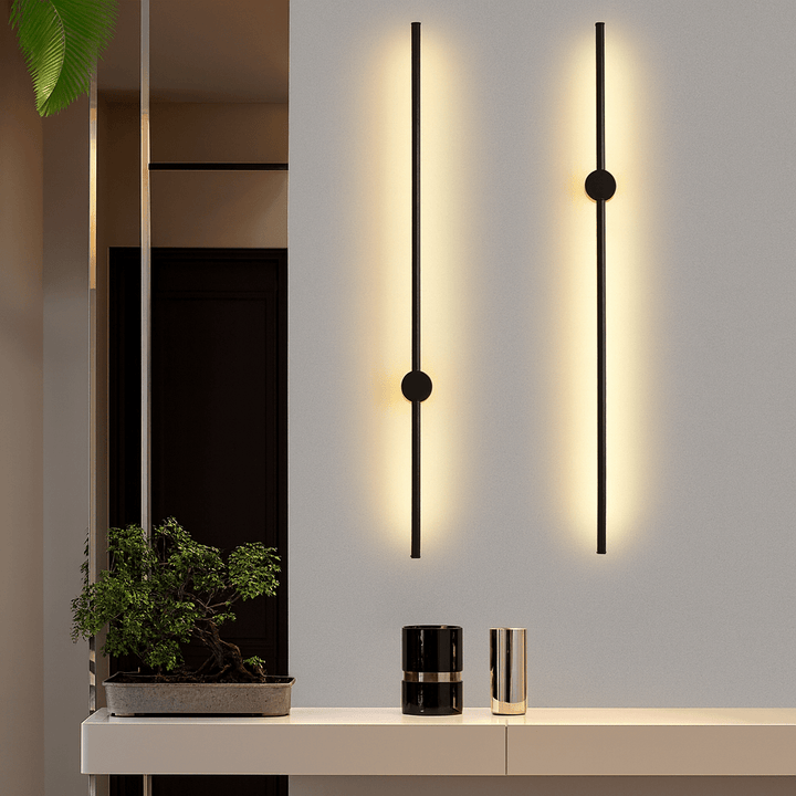 Two black linear LED wall sconces mounted on a white wall above a credenza