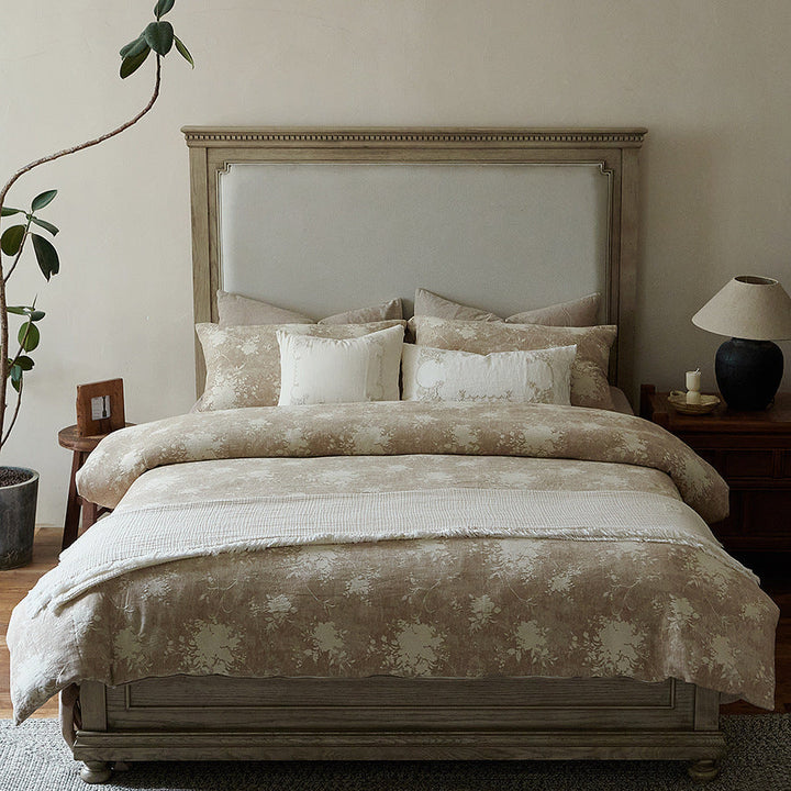 Close-up of the botanical duvet cover and draped bedspread in natural tones