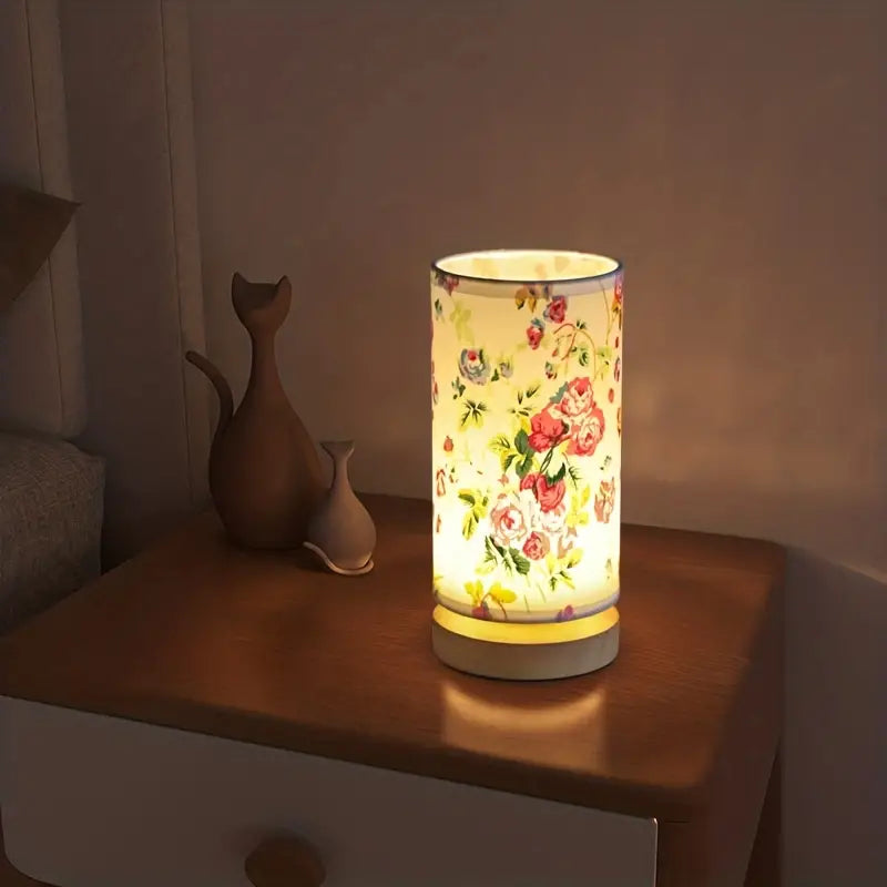 Floral patterned cylindrical night light on a wooden bedside table