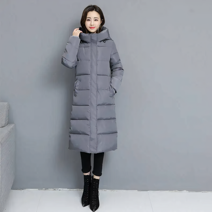 Woman standing in a grey long puffer jacket with front pockets