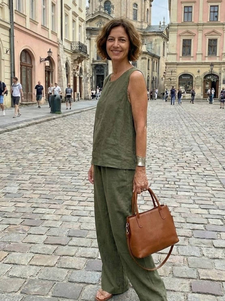 Woman posing in a city square wearing a green two-piece outfit with a handbag