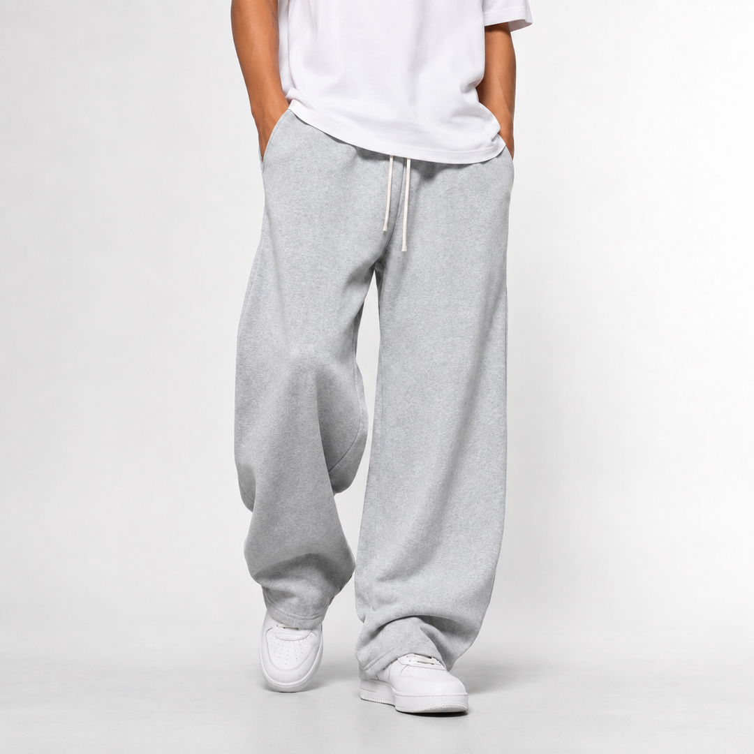 A man wearing light grey loose and long joggers paired with a white t-shirt.