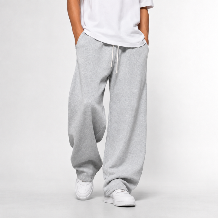 A man wearing light grey loose and long joggers paired with a white t-shirt.