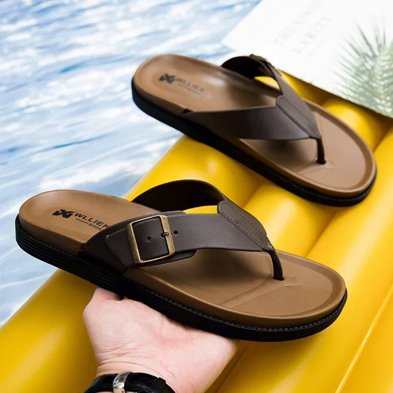 Close-up view of brown men's slide sandals held over yellow surface