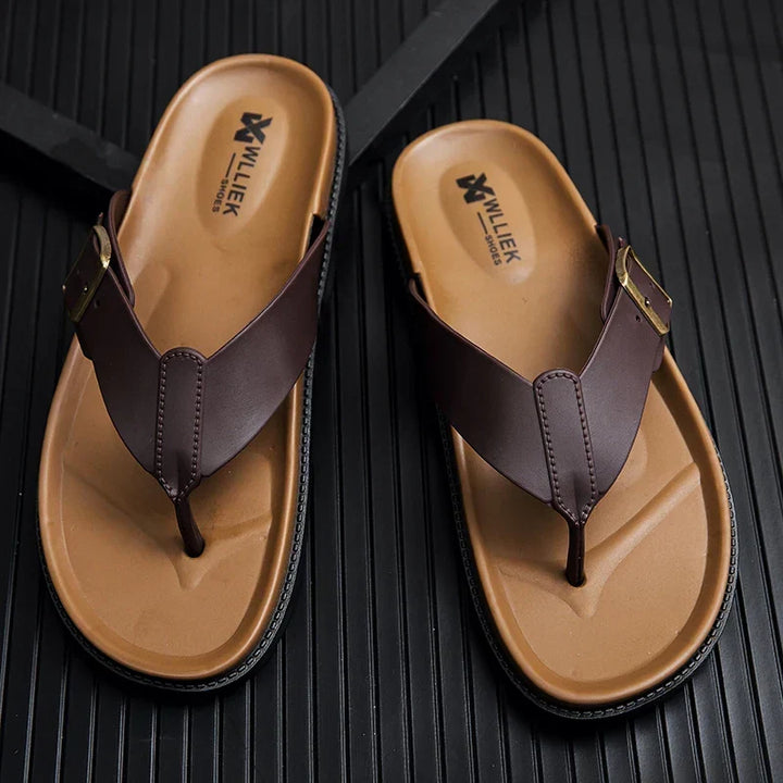 Top-down view of brown men's buckle sandals on textured black background