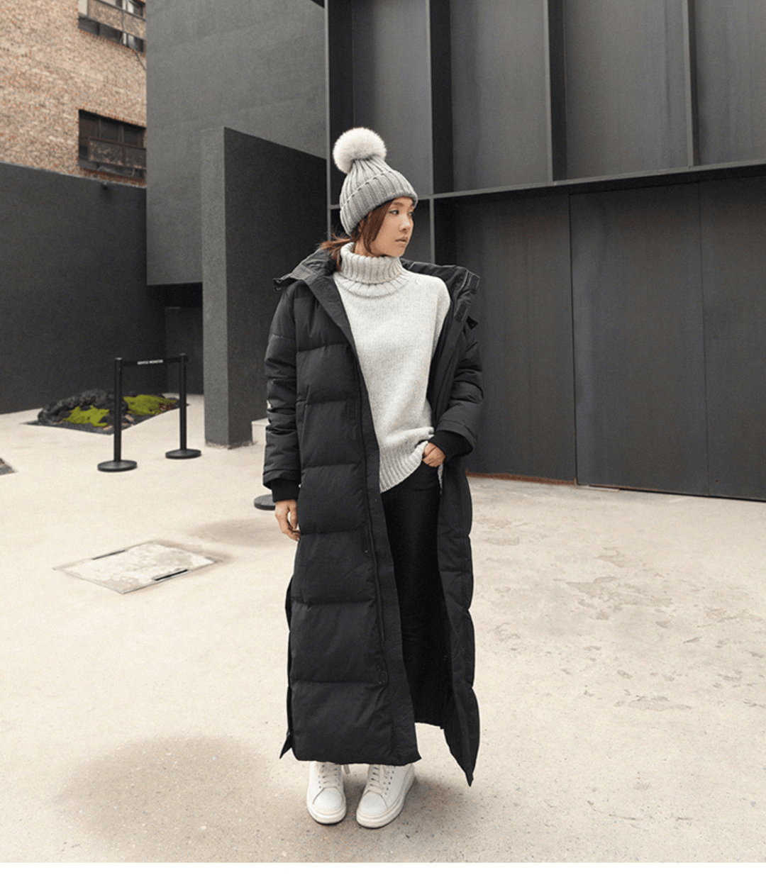Front view of woman in a black long winter parka with chunky knit sweater